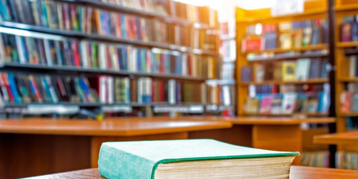A book is sitting on the table in front of some books.